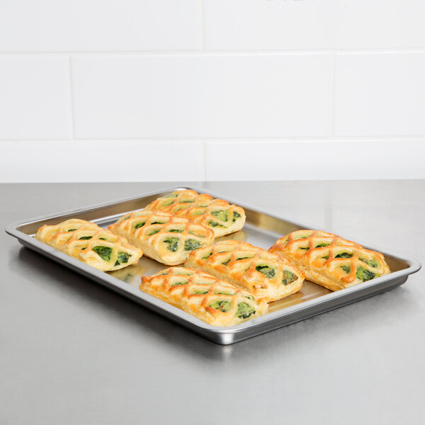 A Waring stainless steel baking pan with four pastry rolls on it.