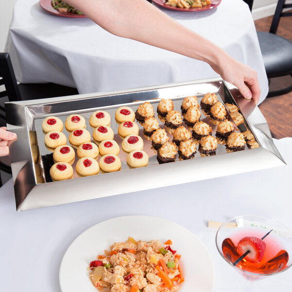 A rectangular stainless steel Vollrath serving tray with food on a table.