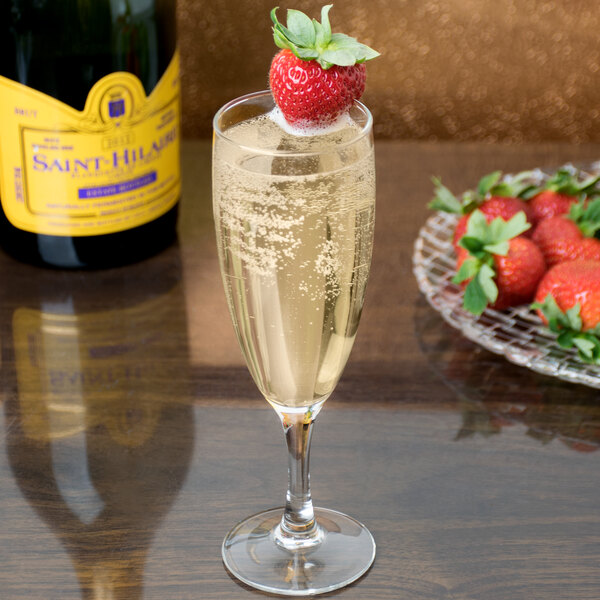 A glass of Arcoroc champagne with a strawberry on top.