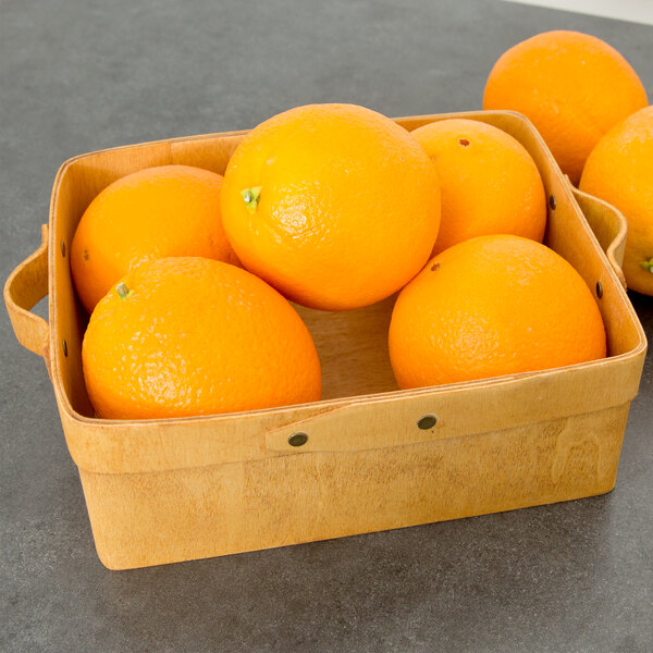 A rectangular American Metalcraft poplar wood basket filled with oranges on a table.