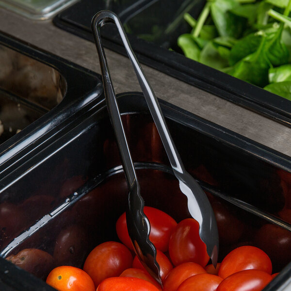 A bowl of cherry tomatoes with Cambro black scallop grip plastic tongs in a container.