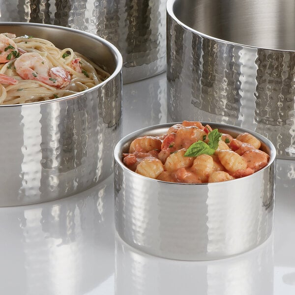An American Metalcraft stainless steel bowl filled with food on a table with other bowls.