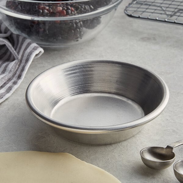 An American Metalcraft aluminum pie pan on a counter with a bowl and measuring spoons.