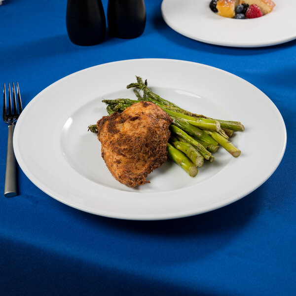 An Arcoroc Rondo service plate with chicken and asparagus on a table.