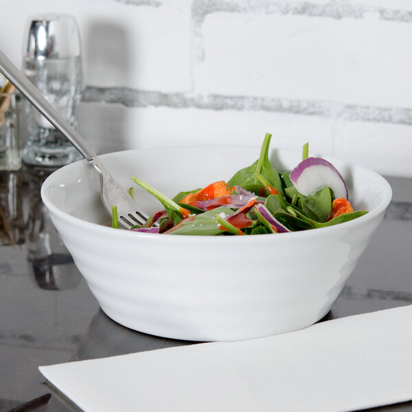 A white 10 Strawberry Street Swing porcelain cereal bowl with a fork in it filled with salad.