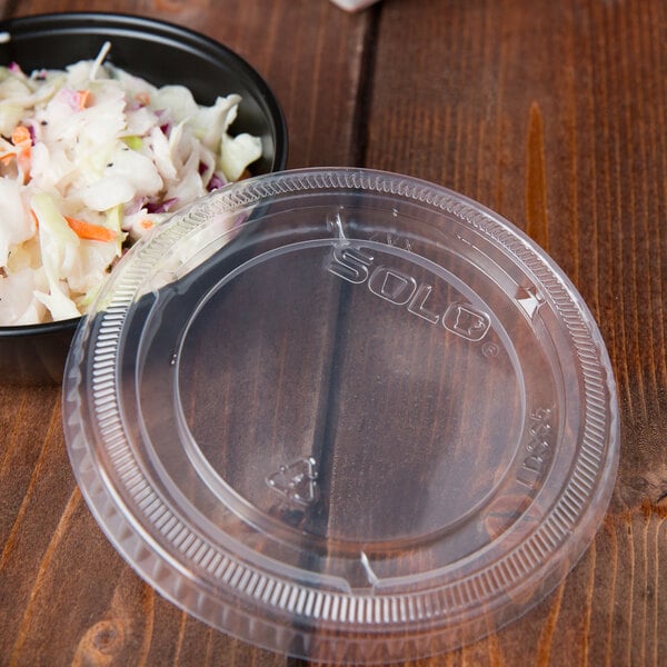 A bowl of coleslaw with a Solo Snaptight lid on a table.