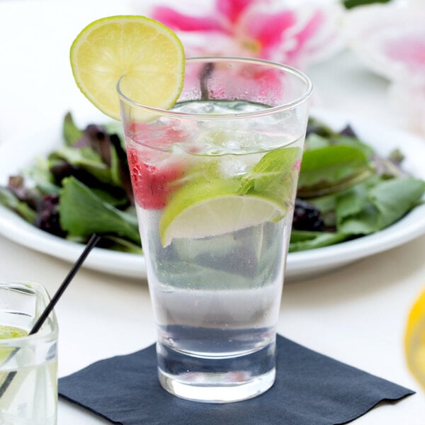 A close-up of an Arcoroc Shetland highball glass of water with lime slices on top.