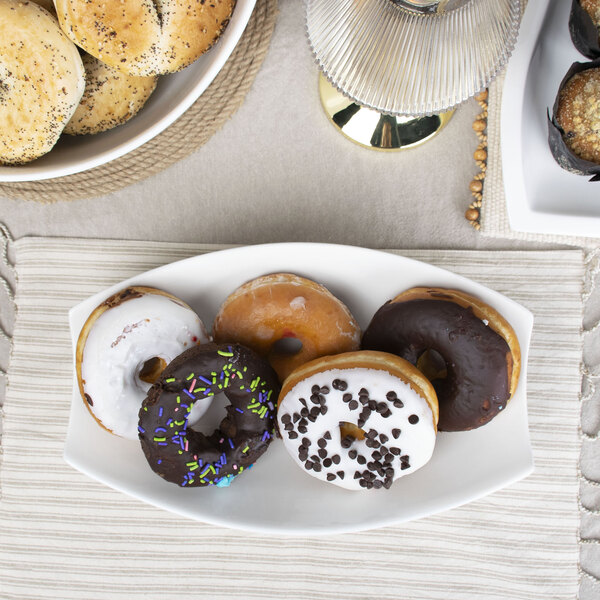 A rectangular white porcelain bowl filled with donuts on a table.