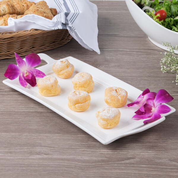 A white rectangular porcelain handled platter with pastries on it.