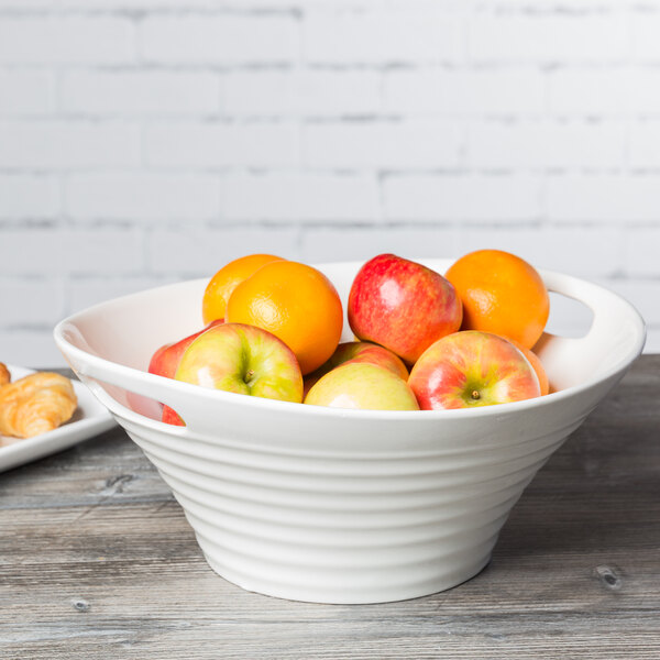 A white Oslo deep handle bowl filled with apples and oranges on a table.