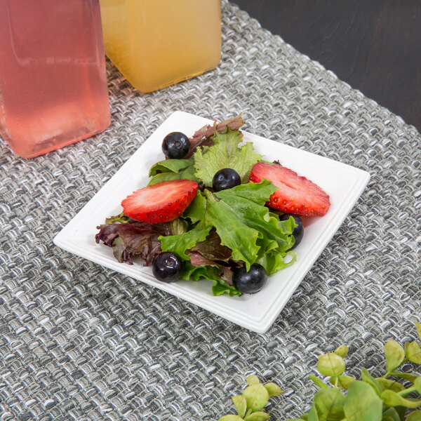 A white 10 Strawberry Street porcelain tray with a salad of strawberries, blueberries, and grapes.