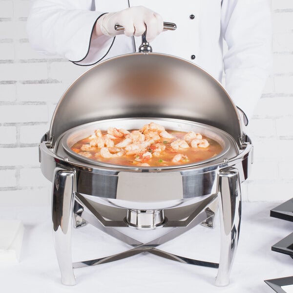A chef using a Vollrath round stainless steel chafer to serve food.