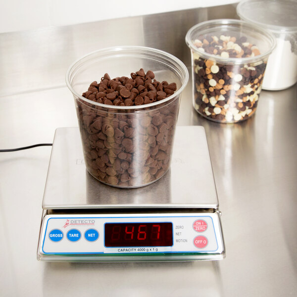 A Cardinal Detecto portion scale with a plastic container of chocolate chips on it.