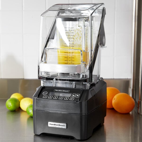 A Hamilton Beach commercial blender with a clear container of orange juice on top.