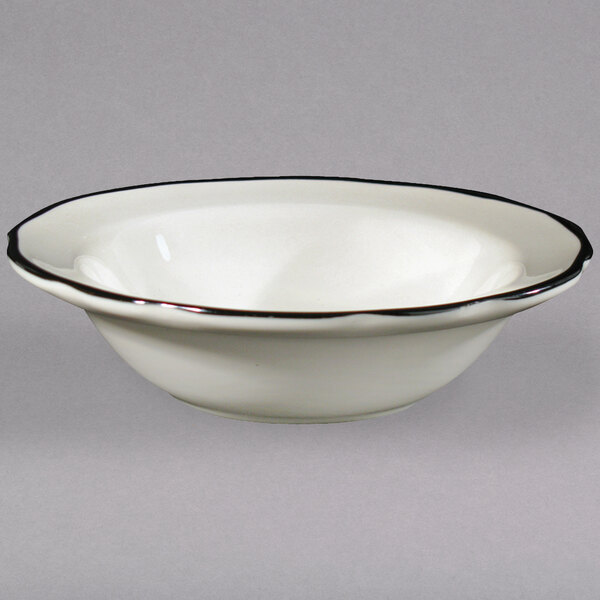 A CAC ivory china bowl with scalloped edges and a black rim.