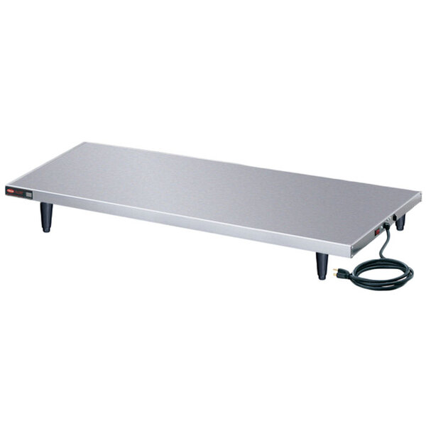 A white rectangular table with a Hatco stainless steel heated shelf on top.