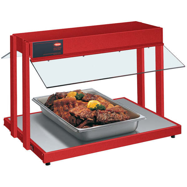 A Hatco red countertop buffet warmer with a tray of meat and lemon wedges.