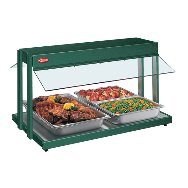 A Hatco green buffet warmer with trays of meat and vegetables.