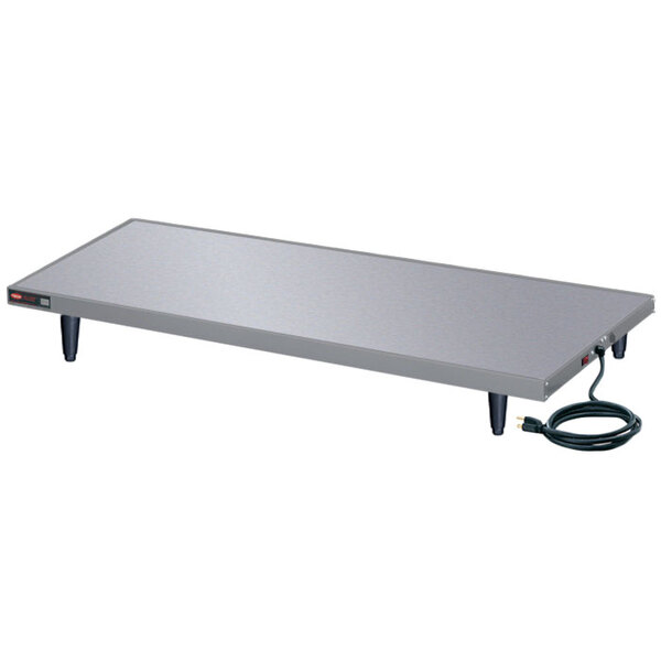 A rectangular stainless steel Hatco heated shelf warmer on a metal table with a power cord.