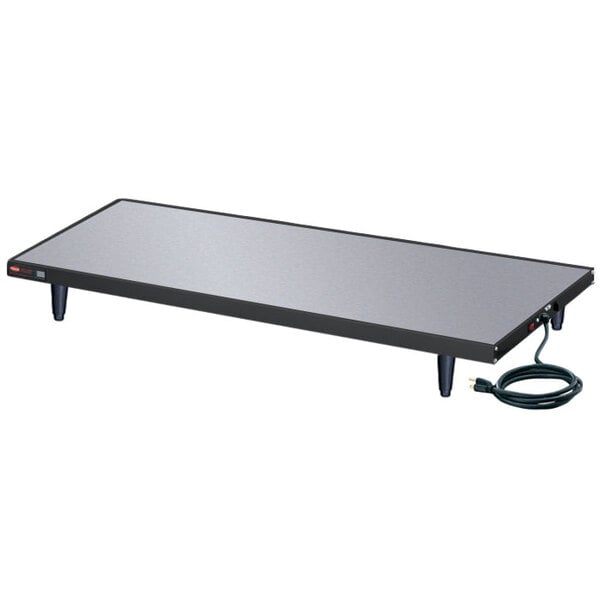A rectangular black Hatco heated shelf on a rectangular table with a cord.