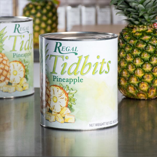 A #10 can of Regal Pineapple Tidbits in natural juice on a white surface.