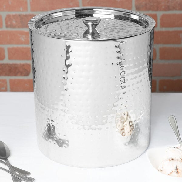 A Vollrath double wall hand hammered stainless steel ice cream chiller with spoons.