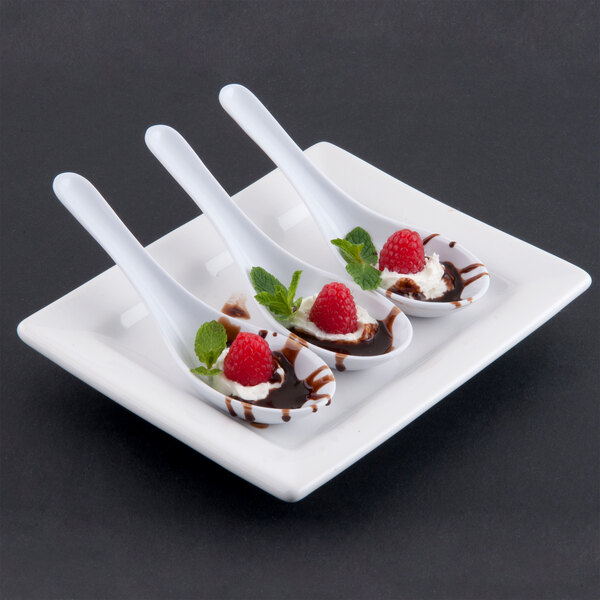 Three Thunder Group melamine Chinese soup spoons with chocolate sauce and raspberries on them.