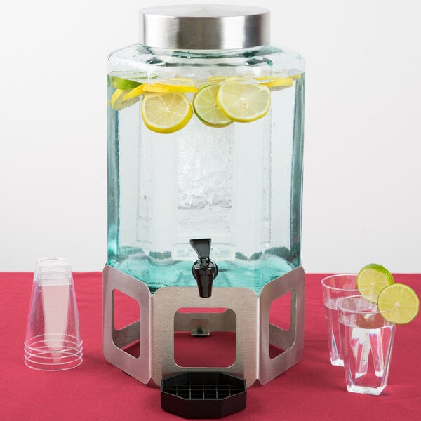 A Cal-Mil stainless steel beverage dispenser with lemons and limes inside.