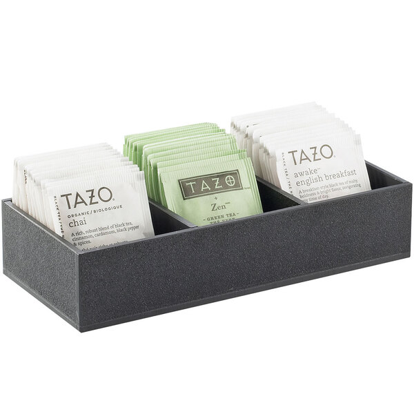 A black Cal-Mil acrylic tray with 3 sections holding packets of tea on a counter.
