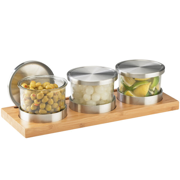 A Cal-Mil bamboo display with three glass jars with metal lids on a white background.