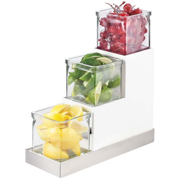 A white metal three-tier jar display with glass containers of lemons.
