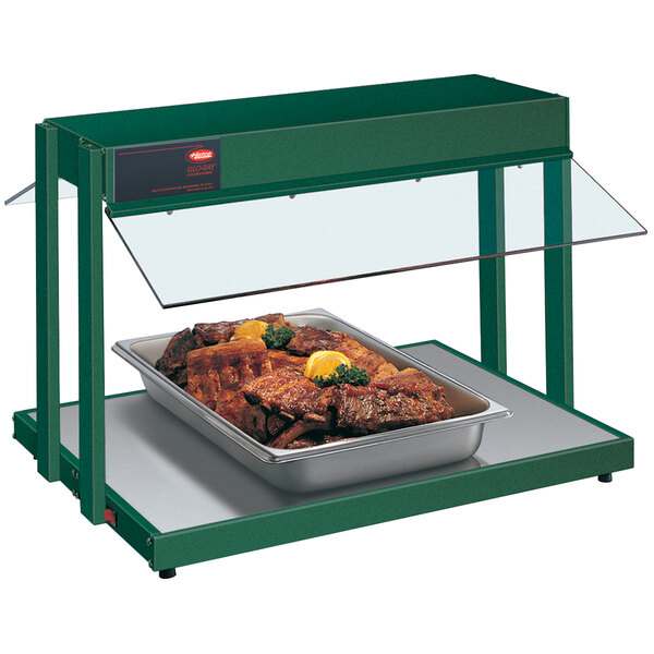 A Hatco green countertop buffet warmer with a tray of meat and lemon wedges.