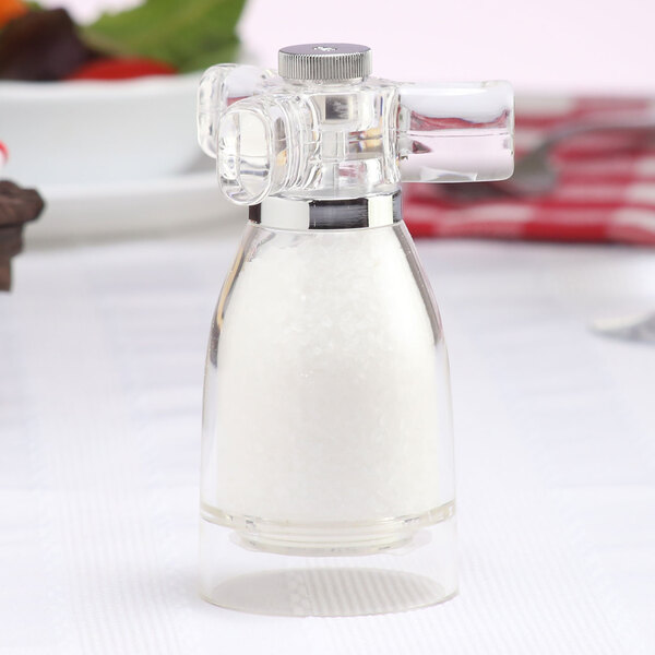A Chef Specialties acrylic salt mill with a silver top on a table.