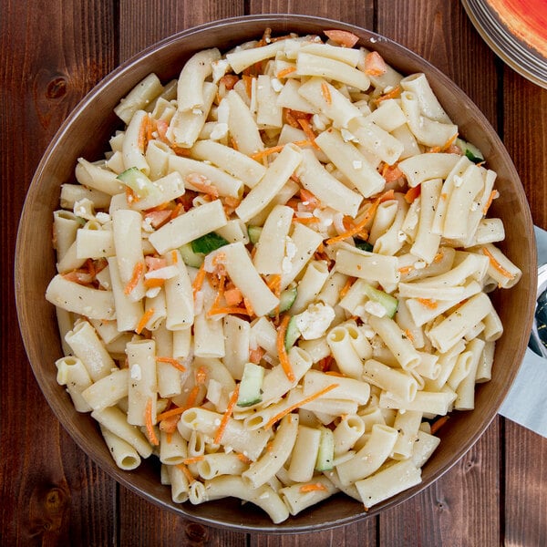 A white bowl of ziti pasta salad with carrots and celery.