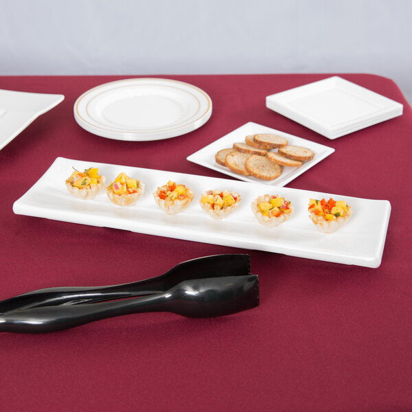 A Tablecraft white rectangular melamine tray with food and a knife on it on a table.