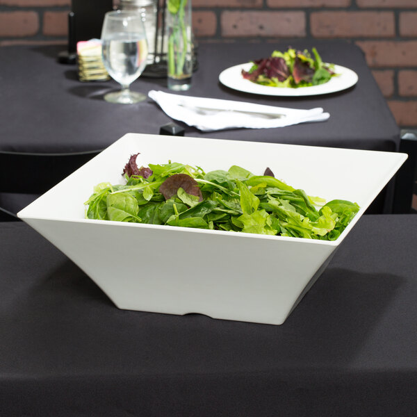A Tablecraft white melamine bowl filled with salad on a table.