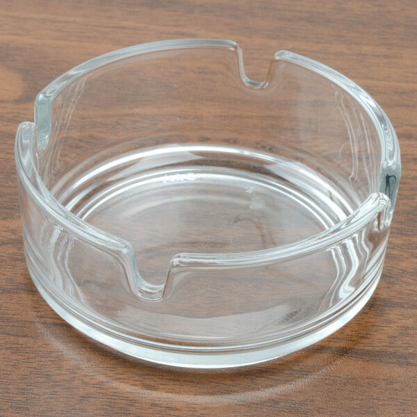 An Arcoroc glass ashtray on a wood surface.