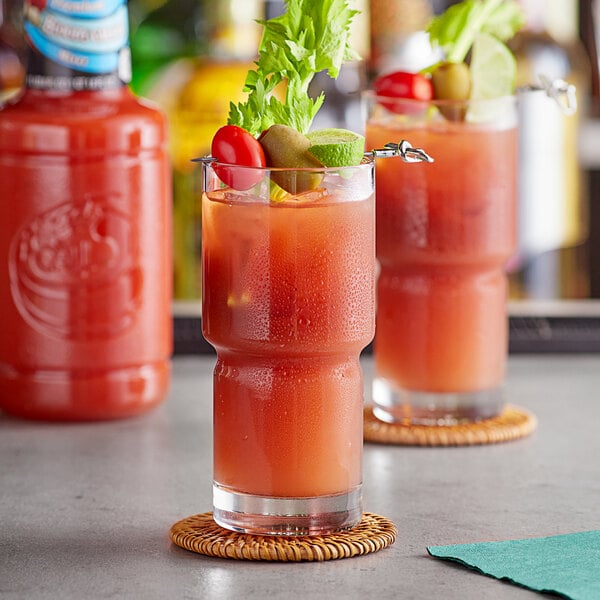A glass of Finest Call Bloody Caesar Mix garnished with a tomato and celery on a coaster.