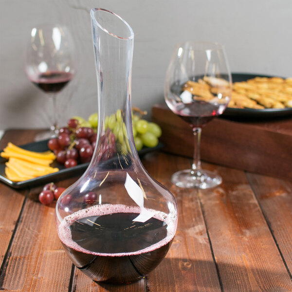 A Chef & Sommelier glass decanter with red wine on a table with food.