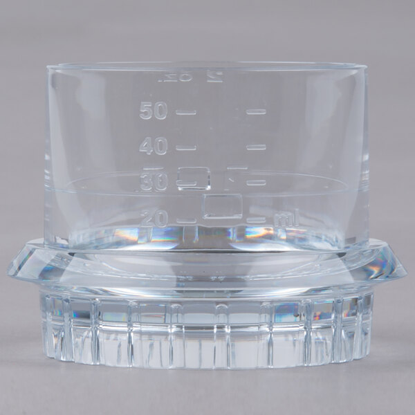 A clear glass beaker with a clear base and numbers on it.
