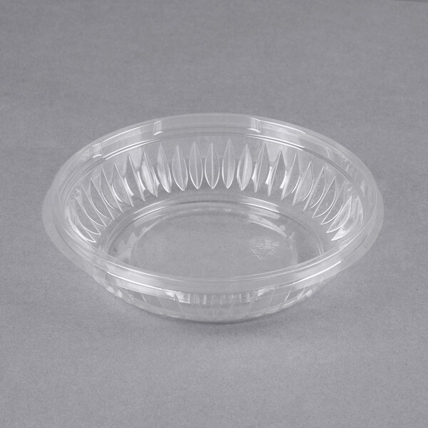 A Dart clear plastic bowl on a gray surface.