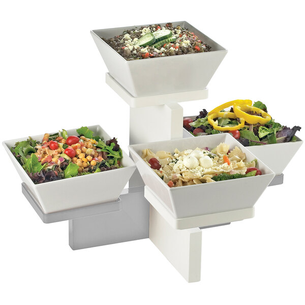 A Cal-Mil stainless steel multi level display with bowls of salad, pasta, and cucumbers on it.
