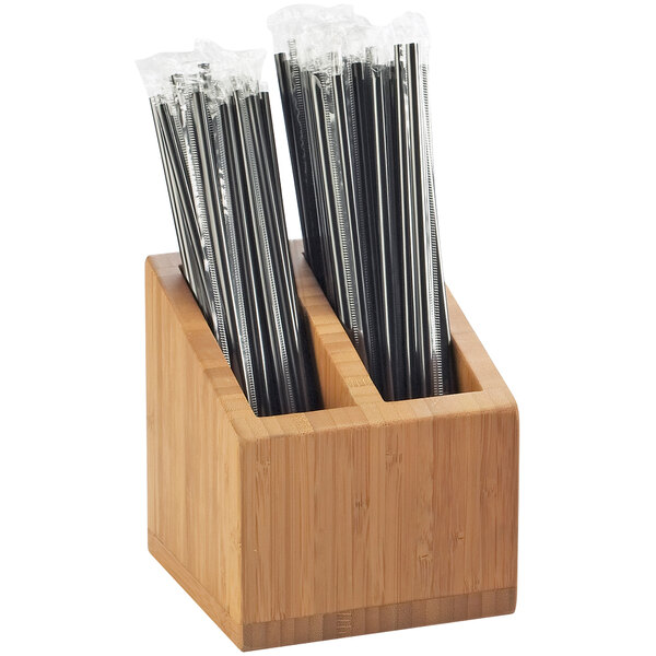 A wooden holder with black straws in it.