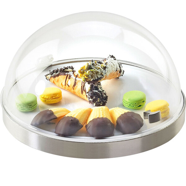 A stainless steel chilled sampler display with a glass dome on a table in a bakery display with pastries inside.
