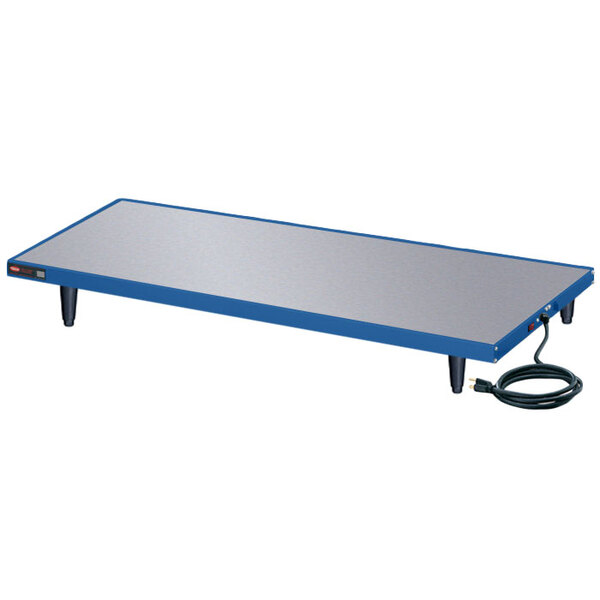 A navy blue and silver rectangular Hatco heated shelf on a white table with a cord.