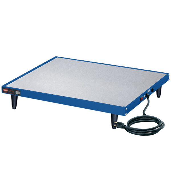 A blue and white rectangular Hatco Glo-Ray heated shelf on a table with a cord attached.