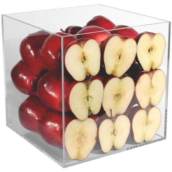 A clear display cube with red apples cut in half inside.