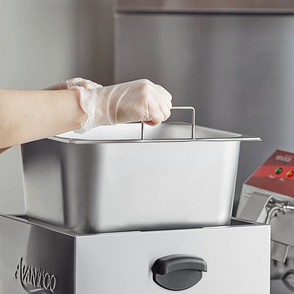 An Avantco oil pan being held in a professional kitchen.
