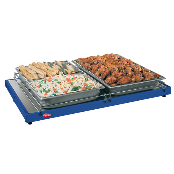 A Hatco navy heated shelf with trays of food on a table.