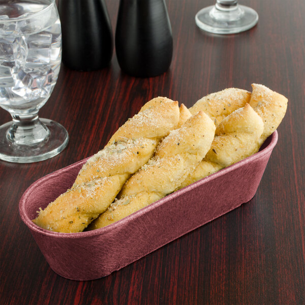 A black breadstick basket filled with bread sticks on a table with a glass of water.